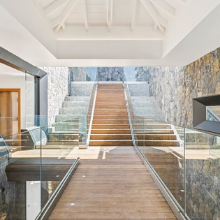 Stunning architectural entrance with natural stone walls and warm wood stairs creating an impressive welcome.