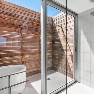 Step into your modern bathroom with a sleek shower and relaxing bathtub, overlooking a private outdoor courtyard for peaceful moments.