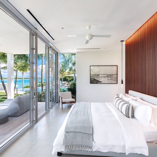 Wake up to stunning sea views through floor-to-ceiling windows, where tropical palms frame your private beachfront paradise.
