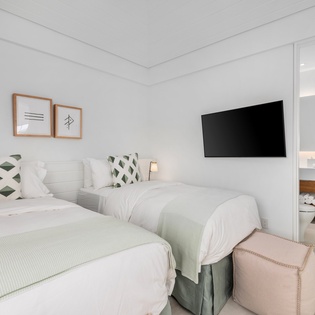 Unwind in your pristine twin bedroom featuring crisp linens, modern amenities, and an elegant ensuite bathroom for ultimate comfort.