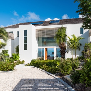 Modern beachfront villa with solar panels and tropical landscaping creates an eco-friendly paradise retreat.