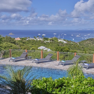 Stunning infinity pool terrace overlooking crystal-blue Caribbean waters and lush tropical landscape.