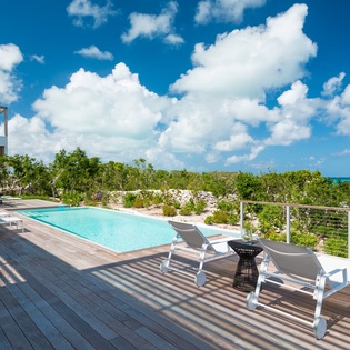 Modern villa's private pool deck offers stunning tropical island views above lush vegetation.