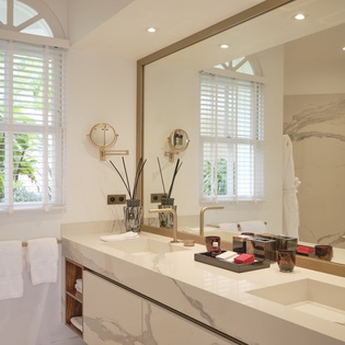 Indulge in your luxurious marble bathroom with dual vanities, elegant fixtures, and natural light streaming through plantation shutters.
