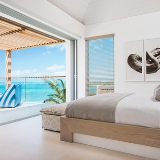 Wake up to endless turquoise waters from your luxurious seaside bedroom, where floor-to-ceiling windows frame paradise perfectly.