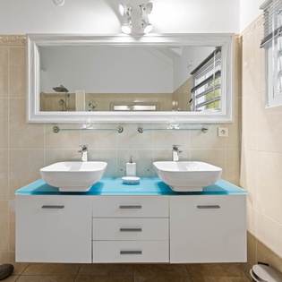 Refresh in your modern dual-sink bathroom with sleek vessel bowls, vibrant blue countertop, and plenty of natural light streaming through.