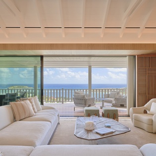 Sink into plush seating while breathtaking ocean views stretch endlessly before you through floor-to-ceiling windows in this elegant living space.