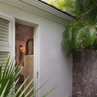 The outdoor shower features lava stone walls and tropical palms, bringing resort-style relaxation to your private retreat.