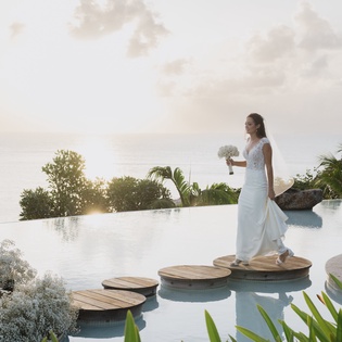 Stunning infinity pool with stepping stones creates a magical backdrop for special moments, surrounded by tropical gardens and ocean views.