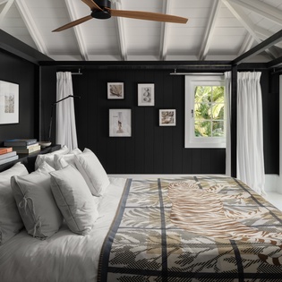 Drift off in this serene bedroom featuring crisp white linens, artistic touches, and tropical views beyond your window.