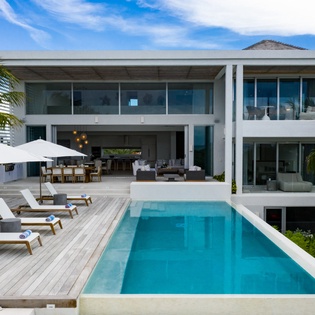 Modern luxury villa featuring pristine pool, tropical gardens, and spacious open-plan living areas perfect for island getaways.