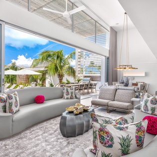 Relax in this stunning open-plan living space where colorful tropical accents meet modern elegance, with panoramic views of swaying palms.