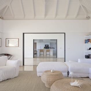 Relax in this bright, airy living space with exposed white beams and plush seating that flows seamlessly into your modern kitchen.