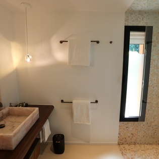 Unwind in your modern sanctuary featuring elegant stone sink, walk-in shower, and warm ambient lighting.