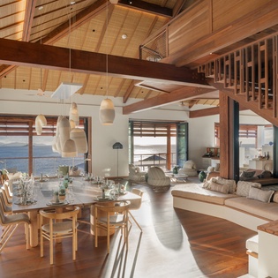 Stunning open-plan living where warm wood beams frame your panoramic ocean views, creating the perfect space for memorable meals.