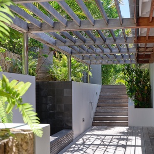 Step into your private outdoor sanctuary where lush tropical gardens meet modern design beneath a stunning pergola.