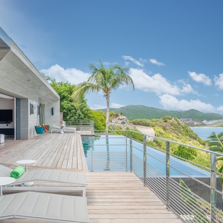 Stunning infinity pool terrace overlooks tropical mountains and turquoise waters, with luxurious loungers for your perfect island escape.