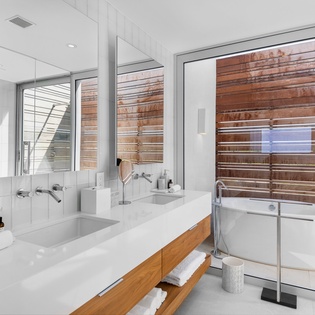 Unwind in your sleek spa-like bathroom with dual sinks, soaking tub, and natural wood accents creating a serene retreat.