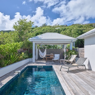 Dive into your private pool paradise, where sun loungers and a hammock await beneath tropical skies for pure relaxation.