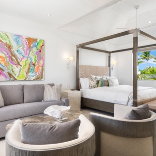 Unwind in your elegant bedroom with tropical views, plush canopy bed, and cozy seating area perfect for morning coffee.