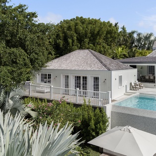 Elegant Caribbean villa with pool deck and tropical gardens set amidst lush palm trees.