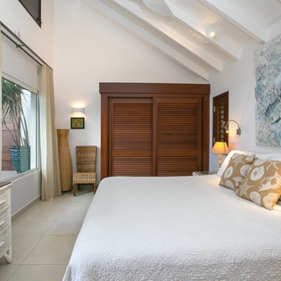 Sink into crisp linens and tropical tranquility in your private bedroom retreat, where vaulted ceilings and coastal artwork invite you to unwind in style.