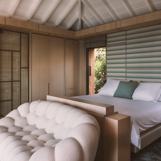 Sink into the plush tufted chair and admire your tranquil bedroom retreat, where warm wood tones and garden views create perfect harmony.