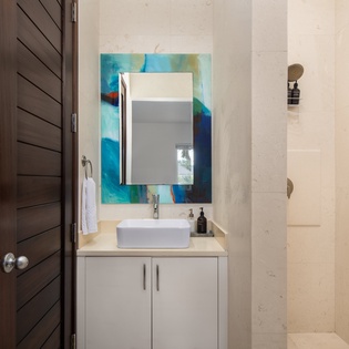Refresh yourself in this sleek modern bathroom featuring a stylish vessel sink, vibrant artwork, and pristine marble surfaces.