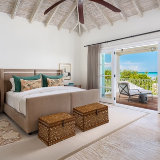 Wake to breathtaking turquoise views through your private balcony doors. This serene bedroom pairs coastal elegance with handcrafted details and airy vaulted ceilings for your perfect island retreat.