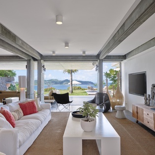 Relax in your stunning living room where floor-to-ceiling windows frame breathtaking ocean views and tropical breezes flow through open spaces.