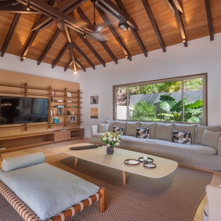 Unwind in your spacious living room with soaring wooden ceilings and tropical garden views through floor-to-ceiling windows.