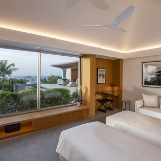 Wake up to tropical views from your luxurious bedroom where floor-to-ceiling windows frame swaying palms and modern comfort meets coastal serenity.