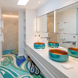 Step into your luxurious ensuite bathroom featuring stunning turquoise vessel sinks and artistic mosaic flooring that creates a spa-like oasis.