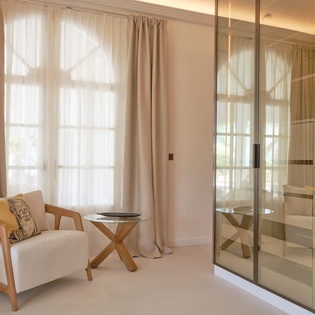 Sink into your stylish reading chair by the window, where warm natural light creates the perfect spot to unwind and enjoy peaceful moments.