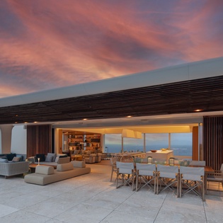 Stunning terrace offers panoramic views with modern outdoor dining and lounge seating under a dramatic sunset sky.