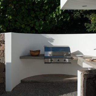 Your private outdoor kitchen awaits with built-in grill, sink, and counter space surrounded by lush greenery for perfect al fresco dining.