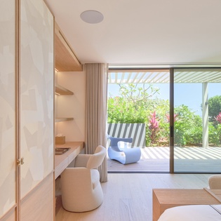 Your spacious living area flows seamlessly to a private terrace surrounded by lush tropical gardens and vibrant plants.