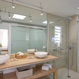 Your stylish ensuite bathroom features dual vessel sinks on warm wood counters and a spacious glass-enclosed shower with sleek modern fixtures.