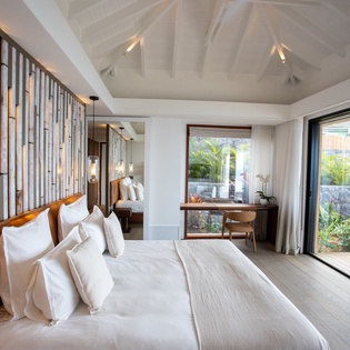 Drift off in your sanctuary with exposed beams, bamboo accents, and floor-to-ceiling windows opening to your private tropical terrace.