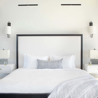 Sink into this serene bedroom where crisp white linens and modern design create your perfect retreat for restful nights.