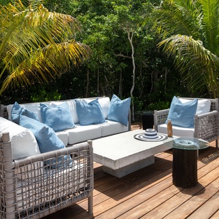 Sink into plush cushions on your private deck, where tropical palms create natural shade for afternoon relaxation and evening conversations.