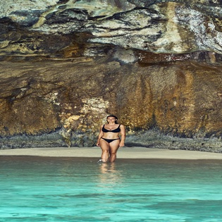 A secluded beach hideaway with pristine turquoise waters and dramatic natural rock formations creates the perfect backdrop for relaxation.