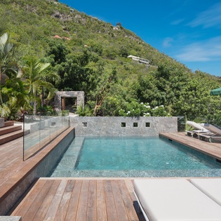 Luxurious infinity pool with tropical mountain backdrop offers serene relaxation surrounded by lush greenery and elegant outdoor lounging spaces.