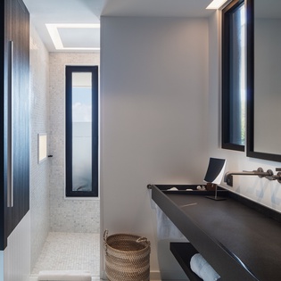 Unwind in your spacious bathroom with dual sinks, elegant black fixtures, and natural light streaming through modern windows.