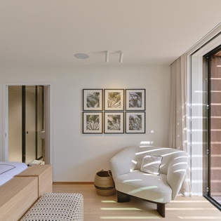 Relax in your serene bedroom suite where natural light dances through sliding doors onto warm wood furnishings and tropical garden views await just steps away.