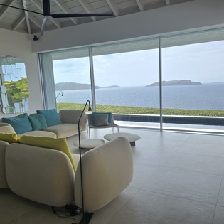 Step into your bright living room where floor-to-ceiling windows frame endless ocean views. Sink into plush seating and let the tranquil blues wash over you—this is your Caribbean escape.