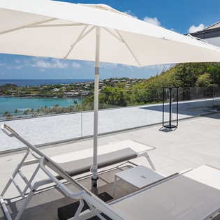 Unwind on your private terrace with breathtaking ocean views, where sun loungers await under crisp white umbrellas for ultimate relaxation.