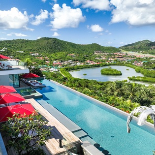 Spectacular infinity pool overlooking tropical mountains, lagoon and lush island landscape