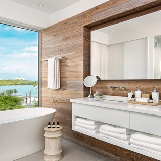 Soak in your luxurious spa-style bathroom with stunning water views, featuring a modern soaking tub and sophisticated wood accents.