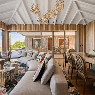 Relax in your luxurious living space featuring soaring wood-beam ceilings, designer lighting, and panoramic windows that frame stunning natural views.